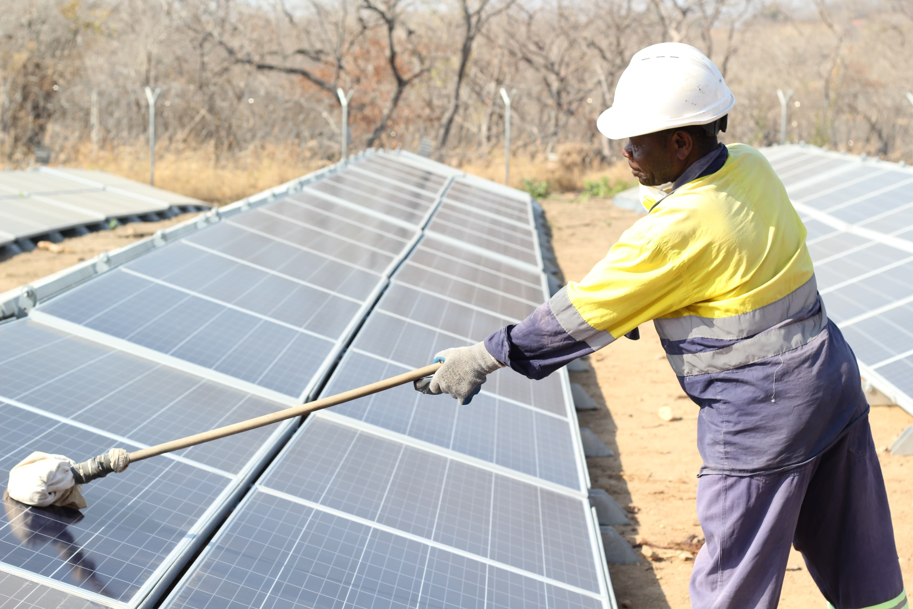 Technician cleaning a solar panel array under the desert sun